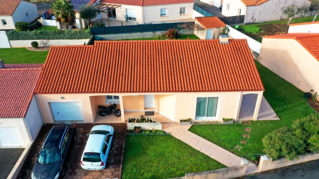 Vue aérienne basse altitude de la façade d'une maison individuelle avec jardin soigné — drone immobilier Tic & Toc Production